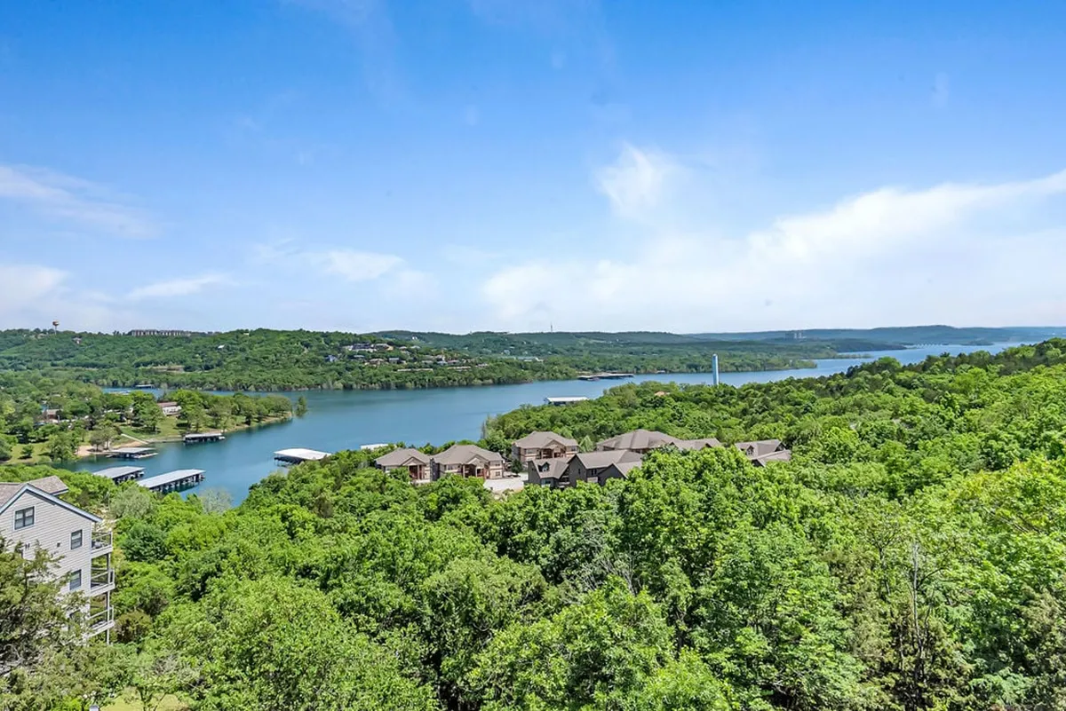 An expansive view of the tranquil lake, framed by lush greenery and gentle hills in the background. The scene hints at boating and lakeside adventures, especially during golden hour.