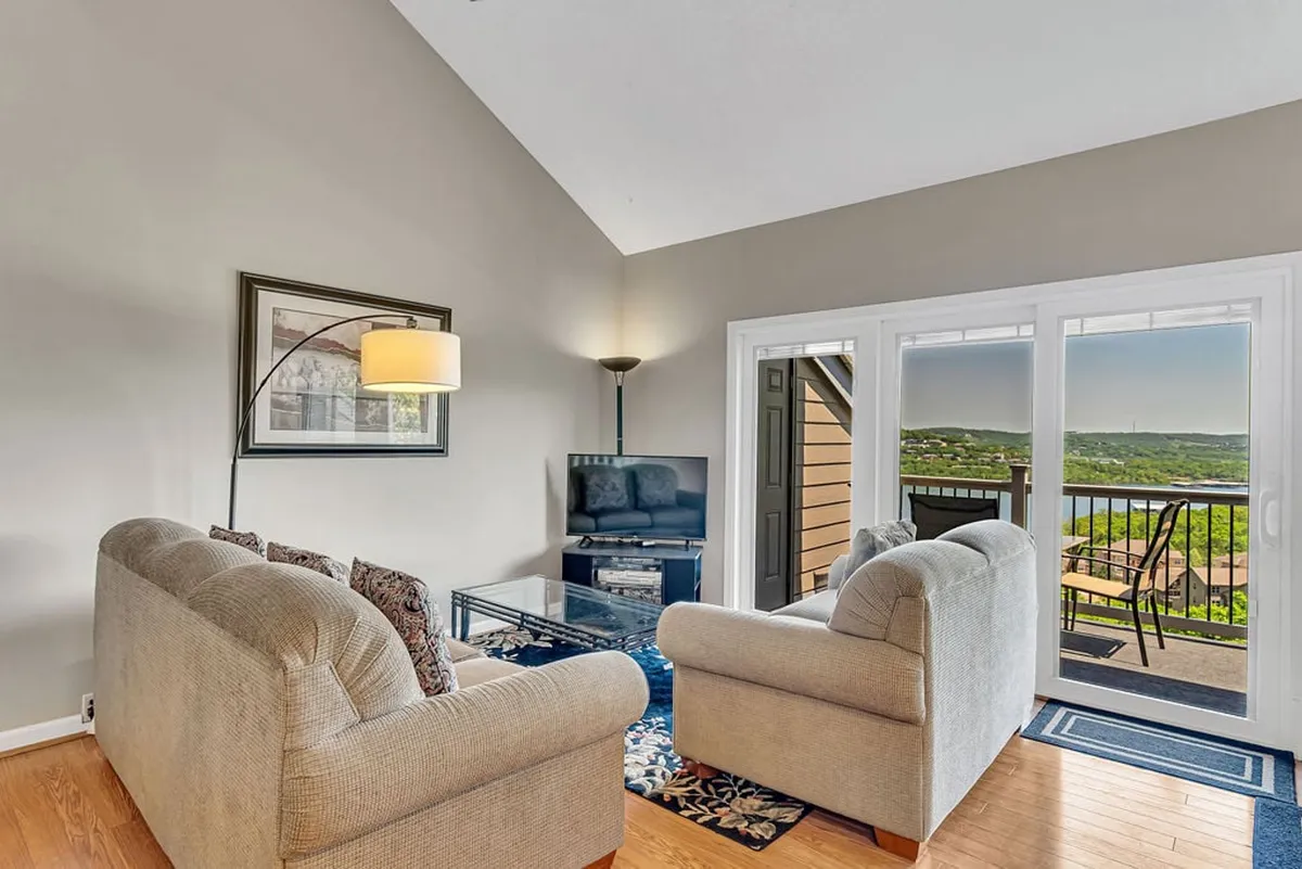 Comfortable sofas and a coffee table are arranged around a television, with a large window providing a view outside. The space evokes serenity, suggesting a restful place to relax and recharge after a day out.