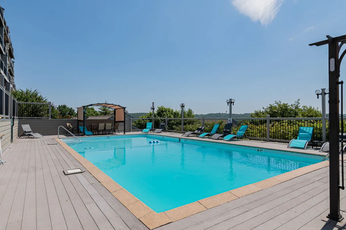 This exterior image features the sparkling outdoor pool surrounded by inviting lounge chairs and a canopy area, set against a scenic backdrop. The pool area exudes a relaxing, resort-like atmosphere ideal for summer leisure and social gatherings.