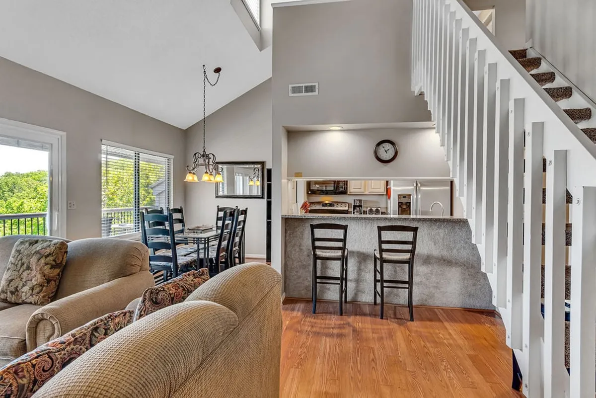 An open-concept space combining the living area, dining table, and kitchen counter, all visible in a single view. The sofa faces the dining table, while the kitchen is seamlessly integrated, encouraging interaction and connection among guests.