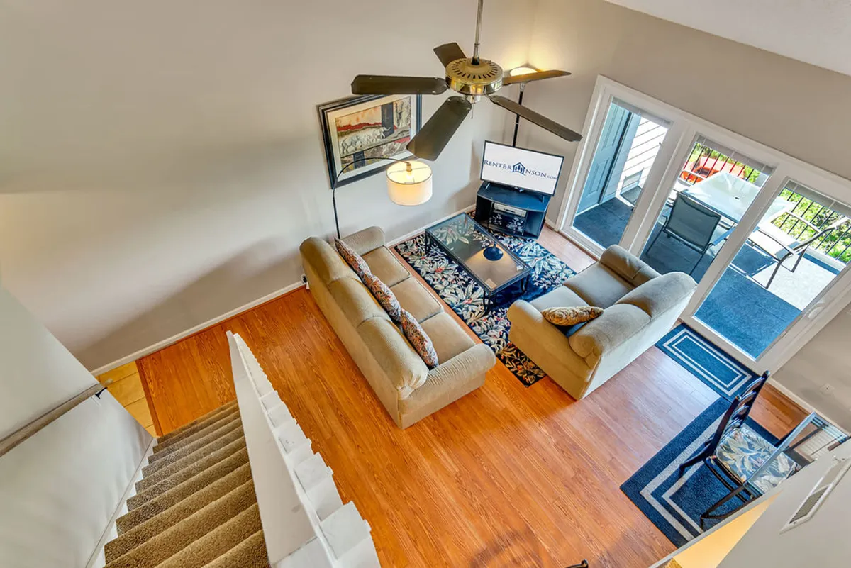 A cozy living area with a sofa set and coffee table faces a television, while large windows offer a glimpse of the outdoor patio. The scene feels inviting for relaxing, hosting friends, or enjoying downtime after exploring local attractions.